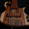 The custom bass body at a low angle showing string thru holes, bridge, pickup and fingerboard