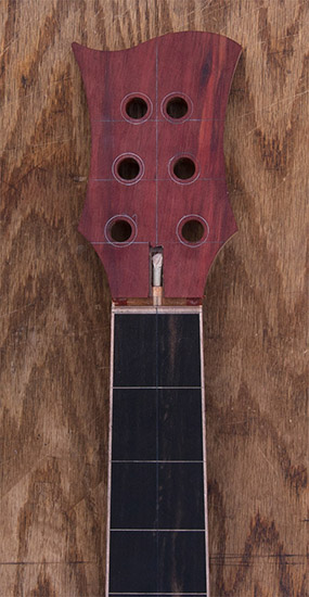 Bloodwood headstock of a 6-string custom bass guitar