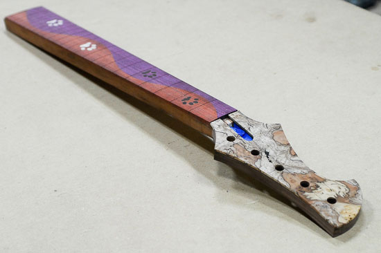 Custom bass neck with dog paw inlays and melted fretboard