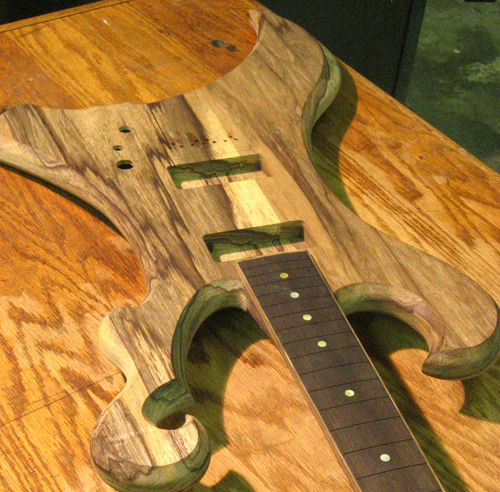 Black limba body, ebony fretboard w/ gold MOP markers, and black limba binding from the front of the custom guitar