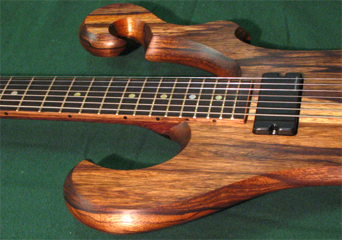 The upper horn, ebony fretboard, neck pickup and fret markers of the custom guitar from the side