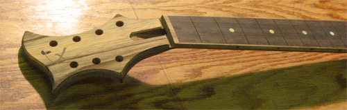 The custom guitar's black walnut neck with ebony fretboard, black limba binding and headstock veneer and gold MOP fret markers