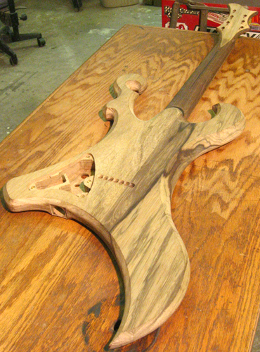 Back of the custom guitar at a low angle from the bottom showing body contours, string thru holes and control cavity